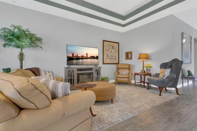 living area with wood finished floors, baseboards, and a glass covered fireplace