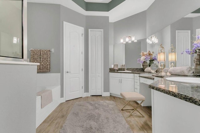 bathroom featuring a bath, wood finished floors, a high ceiling, and vanity