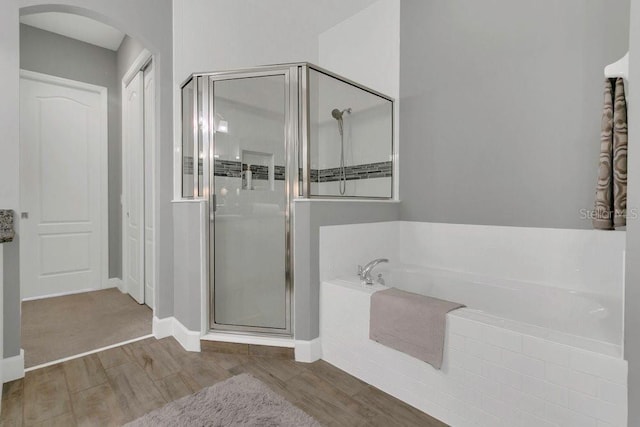 full bath with a shower stall, a garden tub, wood finished floors, and baseboards