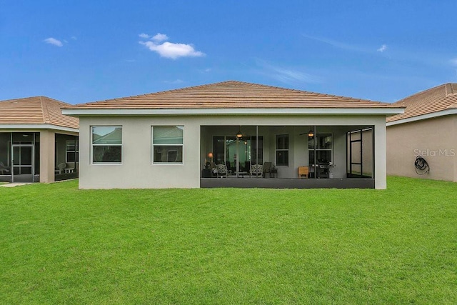 back of house with a sunroom, a yard, and stucco siding