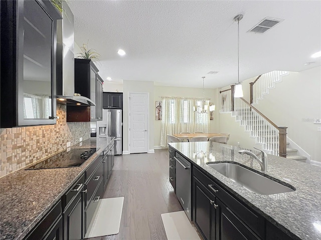 473 Oviedo Blvd, Oviedo, FL 32765 - kitchen featuring a sink, stainless steel appliances, dark cabinetry, wall chimney range hood, and decorative backsplash