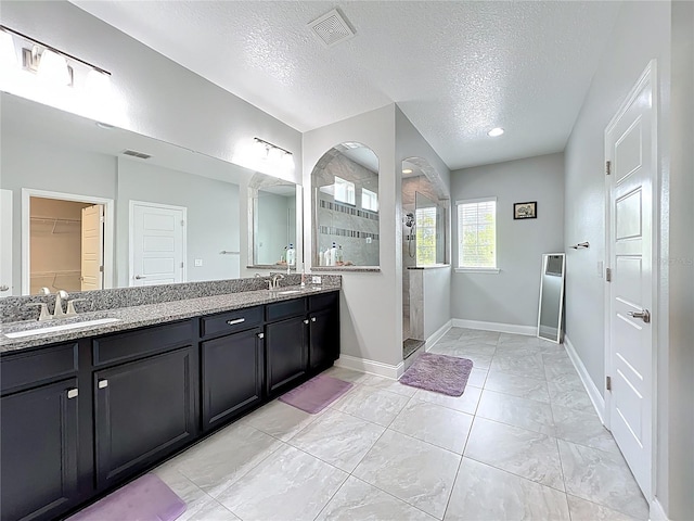 473 Oviedo Blvd, Oviedo, FL 32765 - bathroom featuring a textured ceiling, walk in shower, double vanity, baseboards, and a walk in closet