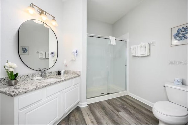 full bathroom with wood finished floors, toilet, a shower stall, vanity, and baseboards