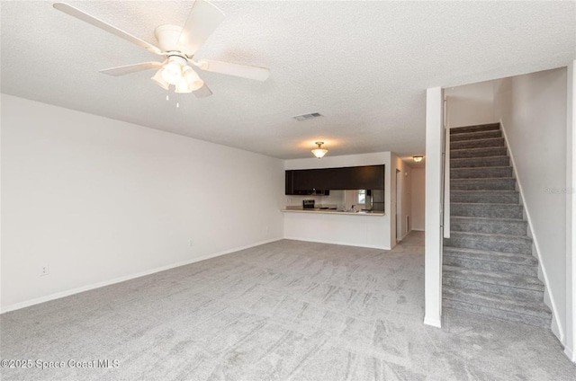 3164 Finsterwald Dr Unit 3164, Titusville, FL 32780 - unfurnished living room featuring stairs, light carpet, a textured ceiling, a ceiling fan, and baseboards
