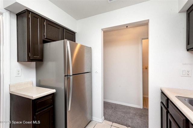 3164 Finsterwald Dr Unit 3164, Titusville, FL 32780 - kitchen with freestanding refrigerator, light countertops, dark brown cabinetry, light colored carpet, and light tile patterned floors