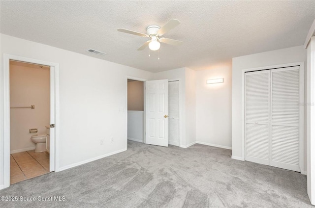 3164 Finsterwald Dr Unit 3164, Titusville, FL 32780 - unfurnished bedroom featuring multiple closets, carpet, ensuite bath, a textured ceiling, and baseboards