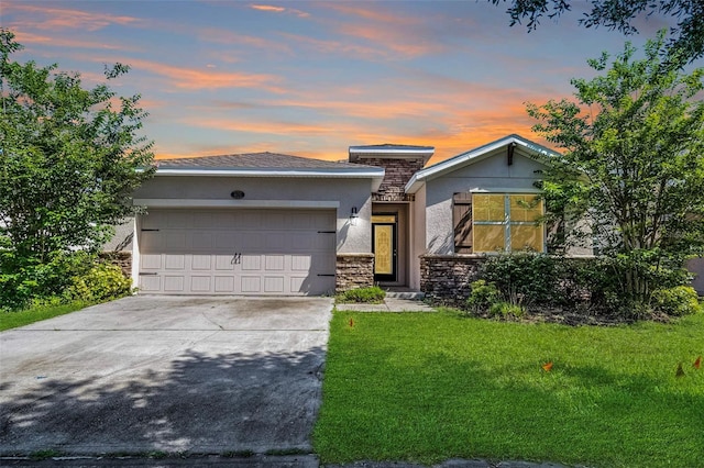 view of front of house with stone siding, stucco siding, an attached garage, concrete driveway, and a lawn