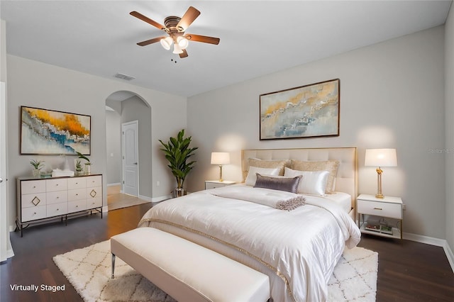 bedroom featuring arched walkways, wood finished floors, baseboards, and ceiling fan