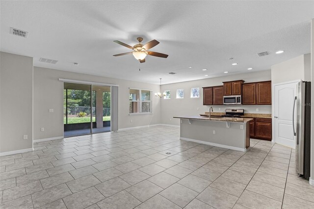 kitchen featuring appliances with stainless steel finishes, a sink, open floor plan, ceiling fan, and healthy amount of natural light
