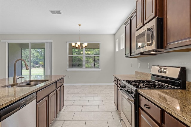 kitchen featuring appliances with stainless steel finishes, a sink, healthy amount of natural light, and baseboards