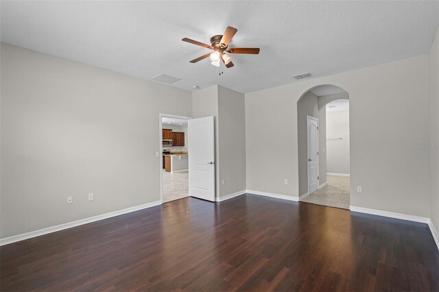 spare room with ceiling fan, arched walkways, wood finished floors, and baseboards