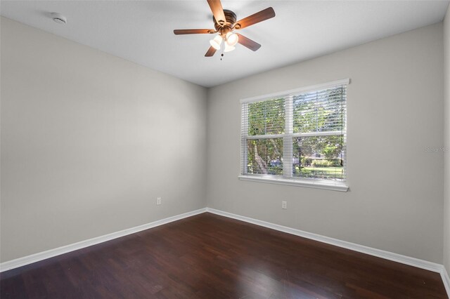 spare room with baseboards, dark wood finished floors, ceiling fan, and a smoke detector