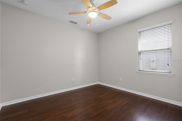 spare room with dark wood-type flooring, baseboards, ceiling fan, and a smoke detector