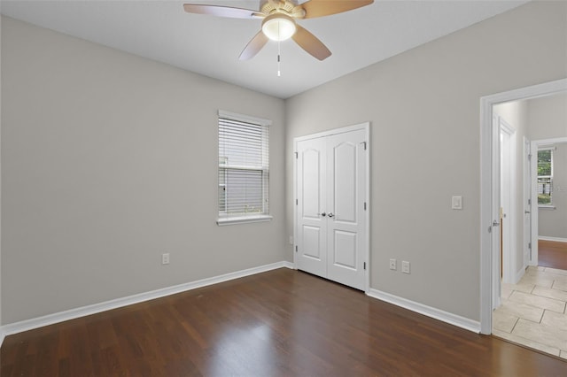 unfurnished bedroom with wood finished floors, baseboards, a closet, and ceiling fan