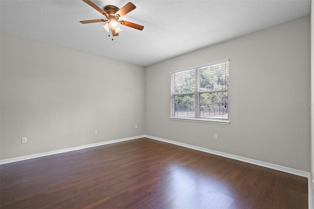 spare room with dark wood-style floors, ceiling fan, and baseboards