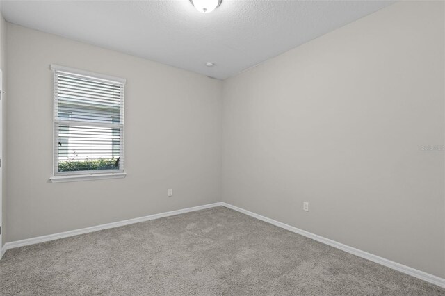 carpeted empty room with baseboards and a textured ceiling