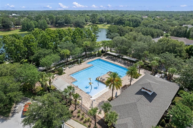 community pool featuring a water view and a wooded view