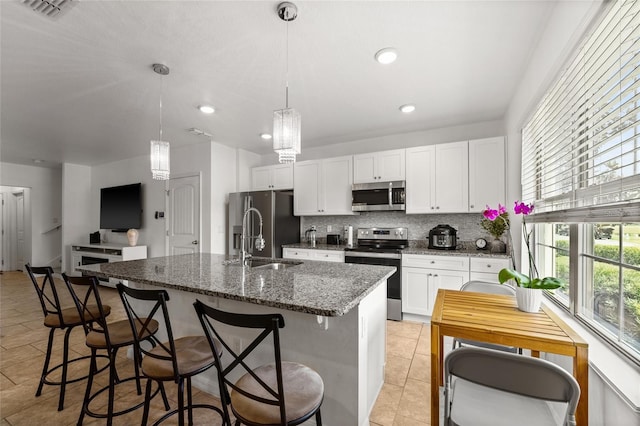16162 Arbor Crest Aly, Winter Garden, FL 34787 - kitchen featuring appliances with stainless steel finishes, a sink, tasteful backsplash, white cabinets, and a kitchen island with sink
