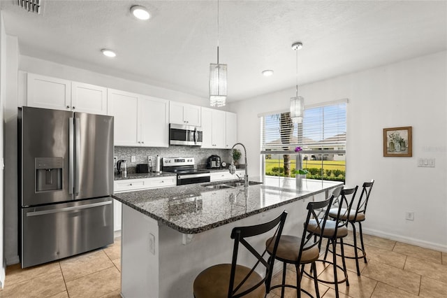 16162 Arbor Crest Aly, Winter Garden, FL 34787 - kitchen featuring appliances with stainless steel finishes, a sink, white cabinets, an island with sink, and a kitchen breakfast bar