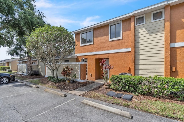 view of property with uncovered parking, stucco siding, and fence