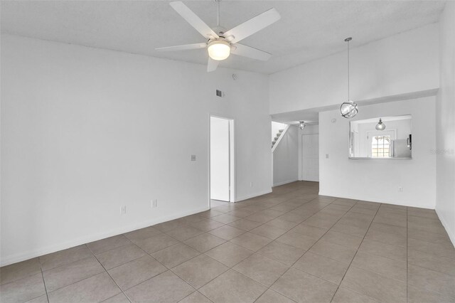 unfurnished living room featuring high vaulted ceiling, stairs, tile patterned floors, ceiling fan, and baseboards