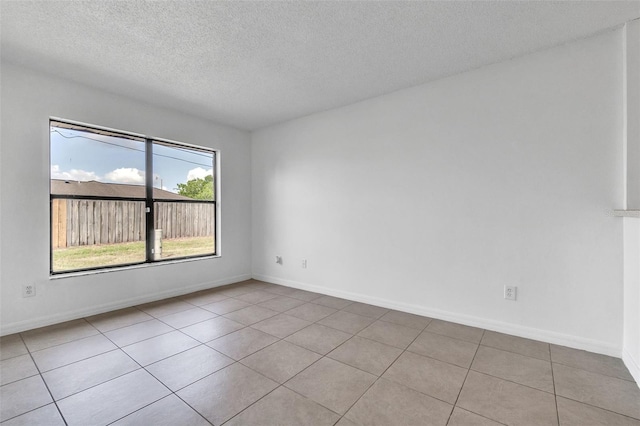 unfurnished room featuring a textured ceiling, tile patterned flooring, and baseboards