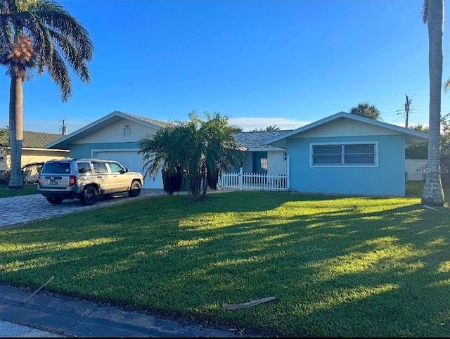 ranch-style house featuring an attached garage, a front lawn, stucco siding, and driveway