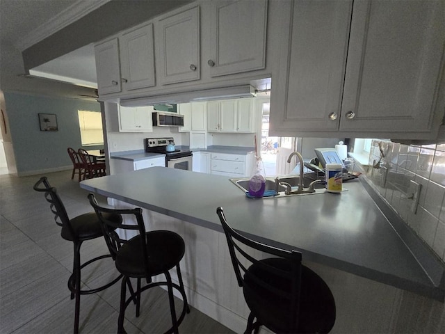 kitchen featuring stainless steel appliances, a peninsula, a kitchen breakfast bar, and baseboards