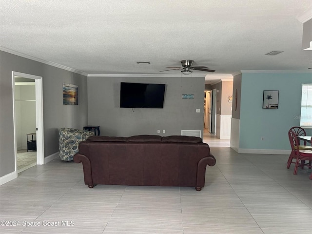living area with a ceiling fan, crown molding, a textured ceiling, baseboards, and light tile patterned flooring