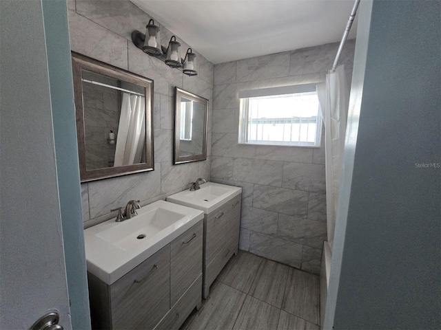 full bathroom featuring tile walls, two vanities, and curtained shower