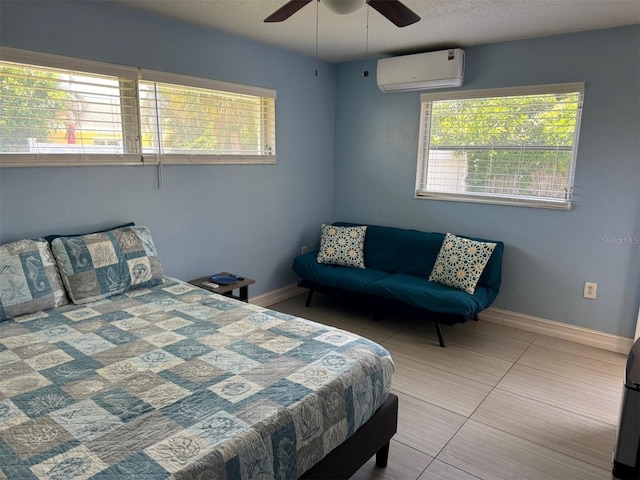 bedroom with a wall mounted AC, multiple windows, baseboards, and ceiling fan