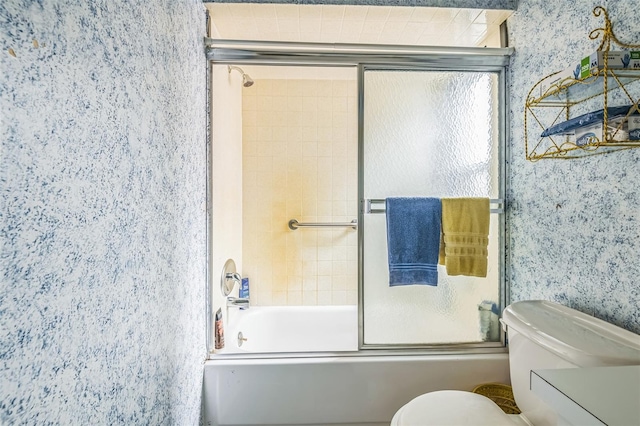 bathroom featuring wallpapered walls, toilet, and shower / bath combination with glass door