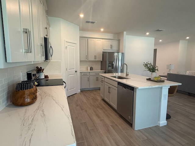 2681 Ginseng Ivy St, Apopka, FL 32703 - kitchen featuring appliances with stainless steel finishes, wood finished floors, light stone counters, backsplash, and recessed lighting