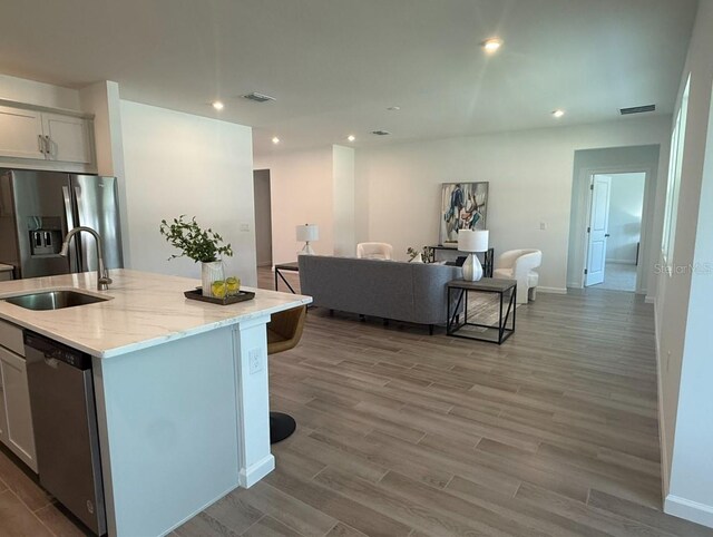 2681 Ginseng Ivy St, Apopka, FL 32703 - kitchen featuring stainless steel appliances, wood finished floors, light stone countertops, recessed lighting, and a center island with sink