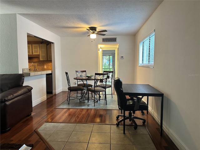 dining area featuring dark wood finished floors, a textured ceiling, ceiling fan, and baseboards