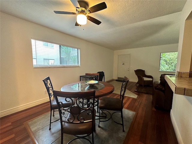 dining area with dark wood-style flooring, healthy amount of natural light, a textured ceiling, and ceiling fan