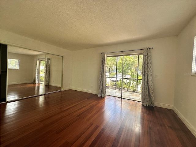 empty room featuring hardwood / wood-style flooring, plenty of natural light, baseboards, and a textured ceiling