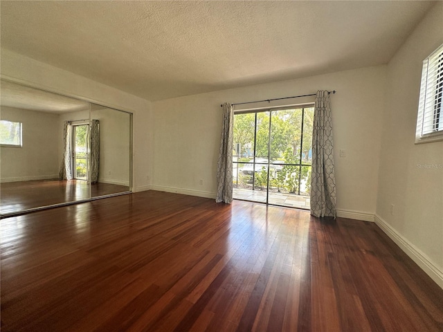 unfurnished room with dark wood-type flooring, baseboards, and a textured ceiling