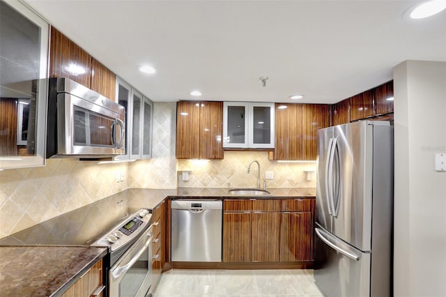 kitchen with appliances with stainless steel finishes, a sink, modern cabinets, dark stone countertops, and recessed lighting