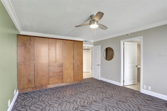 unfurnished bedroom with carpet floors, ornamental molding, baseboards, a textured ceiling, and ceiling fan