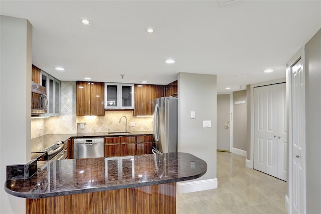 kitchen featuring stainless steel appliances, a sink, a peninsula, glass insert cabinets, and recessed lighting