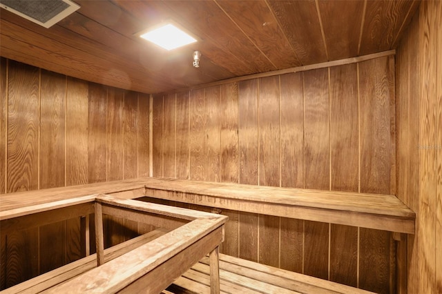 relaxing sauna / steam room featuring wood ceiling and wood walls