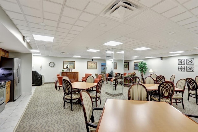 dining area with a paneled ceiling and light colored carpet