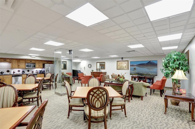 dining space with light carpet and a paneled ceiling