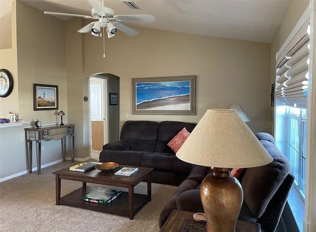 living area with arched walkways, a ceiling fan, carpet flooring, baseboards, and high vaulted ceiling