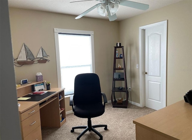office area with a ceiling fan, light colored carpet, and baseboards