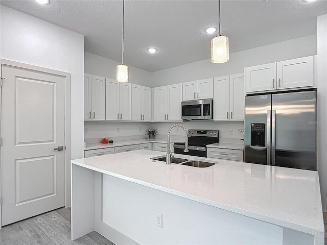16253 SW 29th Court Rd, Ocala, FL 34473 - kitchen featuring stainless steel appliances, a sink, a textured ceiling, light wood-style flooring, and decorative light fixtures