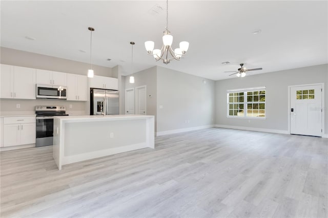 kitchen with appliances with stainless steel finishes, a ceiling fan, white cabinets, a kitchen island, and baseboards