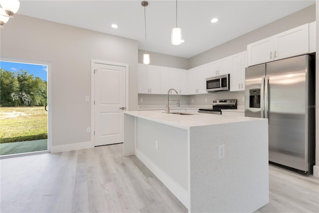 kitchen featuring stainless steel appliances, a sink, light wood finished floors, white cabinets, and recessed lighting