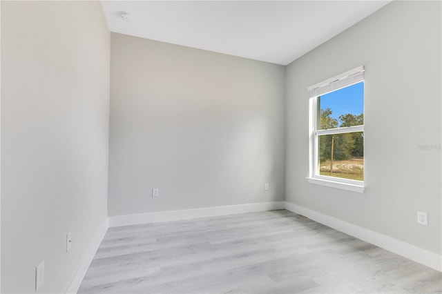 spare room with light wood finished floors, baseboards, and a smoke detector
